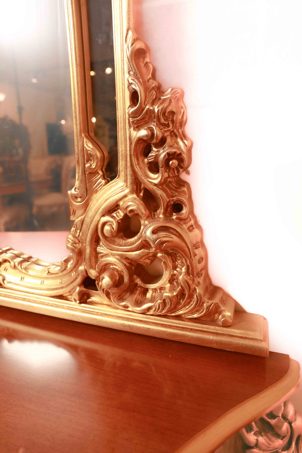 Decorative gold mirror with intricate designs on a wooden surface.
